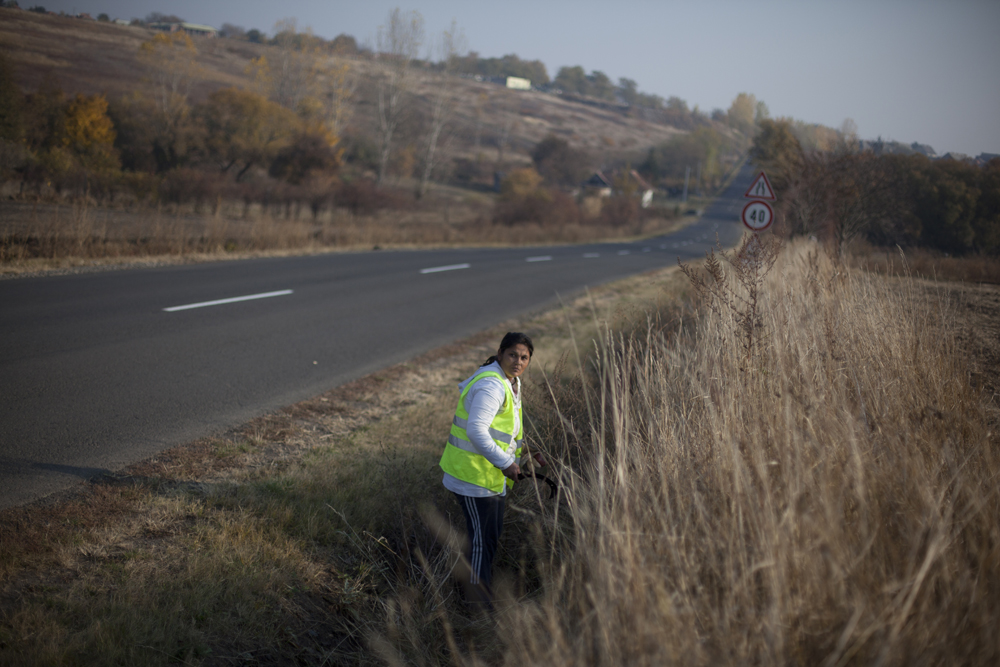 Un petit groupe de femmes nettoie les abords d'une route, Ã la serpe, dans le froid mordant.