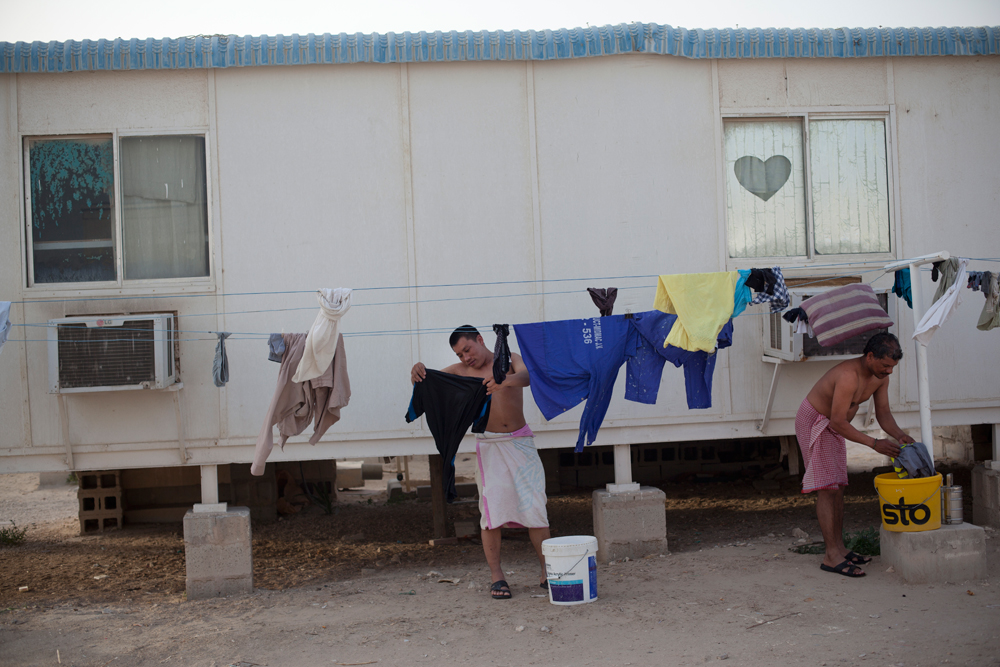 Camp Al Nakhla. Retour des ouvriers à la tombée du jour, après une journée de 10 à 14 heures de travail sur les chantiers de construction.