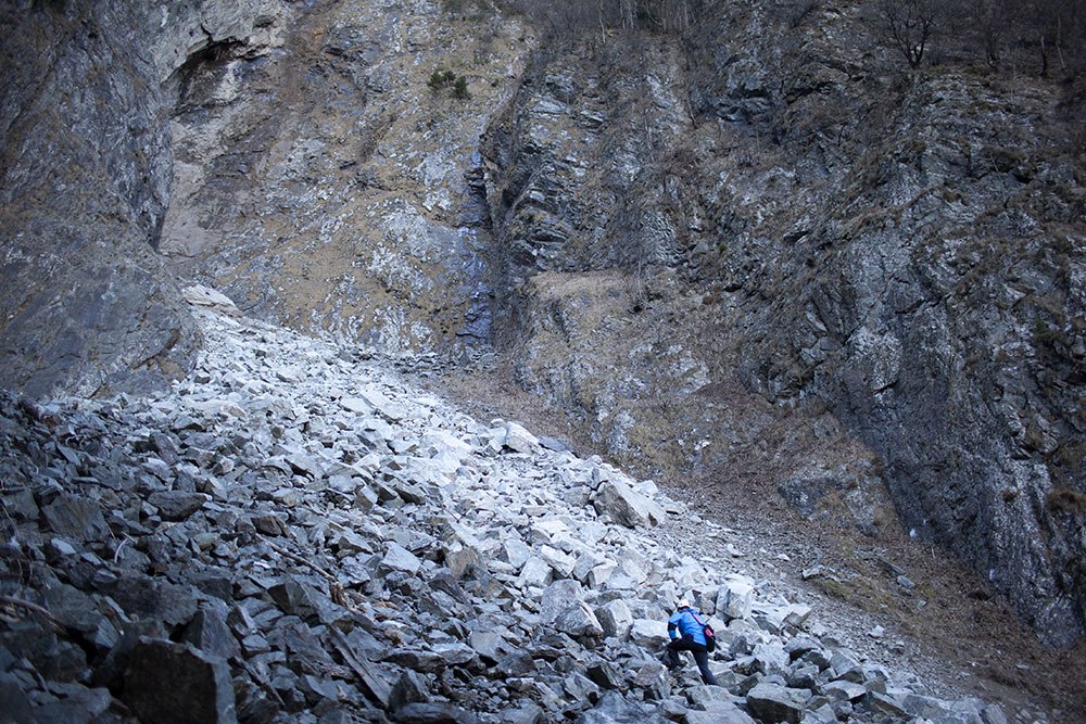 Julien vient prendre la mesure d’un éboulement de 300 m3 (cela représente 25 camions-semi-remorque pleins), à la Rampe des Commères, dans l’Oisans. 
L’éboulement s’est ajouté à d’autres, plus anciens ce qui, finalement, produit un immense pierrier de gros blocs de pierre instables.
