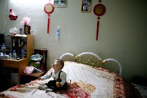Xiao Fei pose son fils Stephane sur le lit. Elle part à la cuisine. Forcément, il se met à pleurer.
