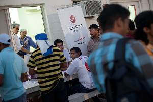 Camp Al Nakhla. Retour des ouvriers à la tombée du jour. Un organisme de transfert d'argent se rend sur le camp pour proposer ses services.